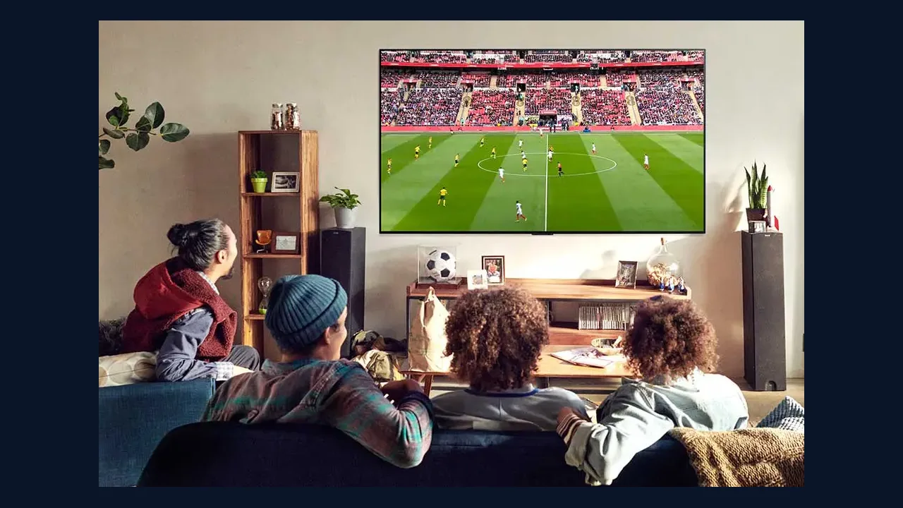 Family watching a soccer match on a large TV in a living room